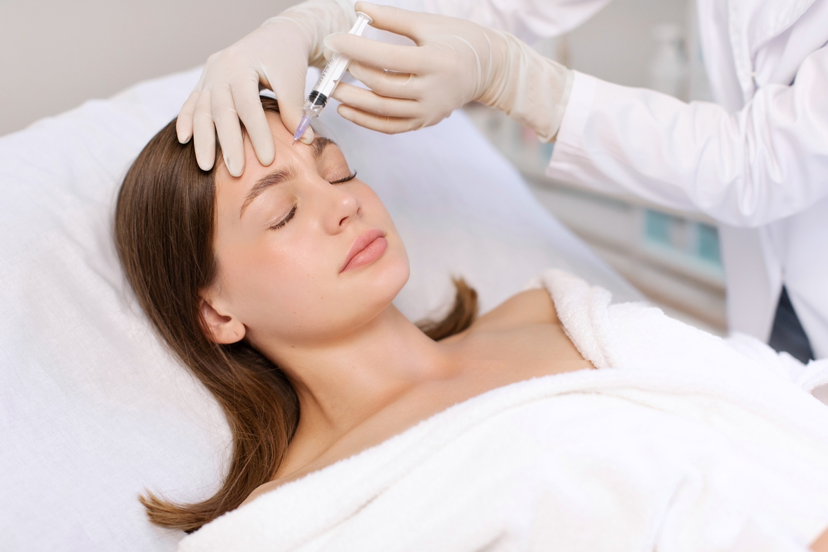 Provider administering a forehead injection to a woman, illustrating Botox in Fishers, IN.